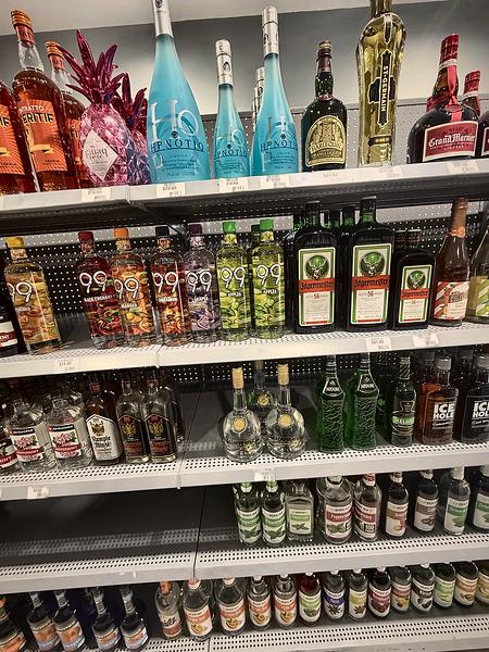 Liqueur shelves with tall decorative bottles on the top row
