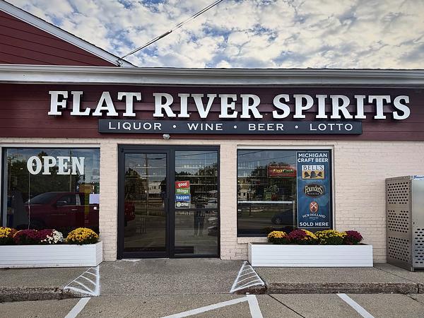 Front entrance with the Flat River Spirits sign reading Liquor, Wine, Beer, Lotto, flanked by flower planters